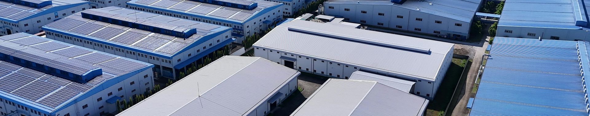 Luftaufnahme einer Fabrik mit Solarpaneelen auf dem Dach.