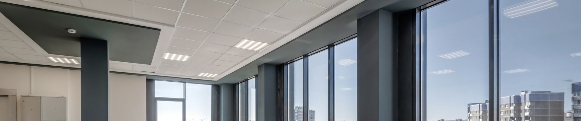 Moderne Infrarotheizung in einem hellen Raum mit großen Fenstern.